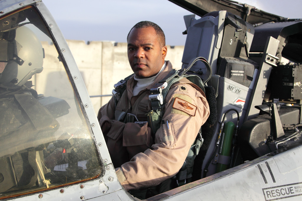 A man in military uniform sitting inside of an airplane.