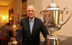 A man standing next to two trophies in front of him.