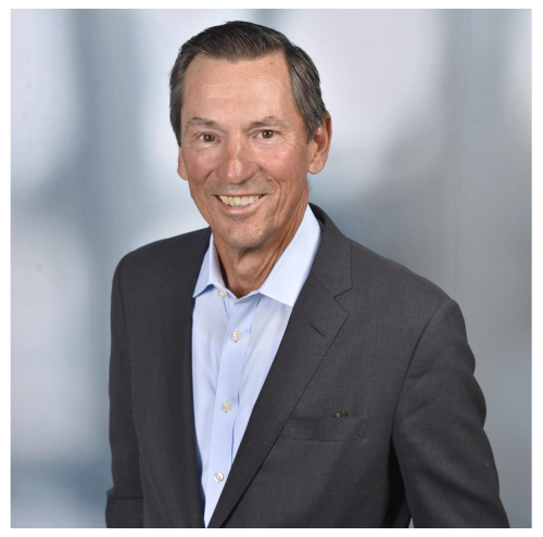 A man in a suit and tie smiling for the camera.