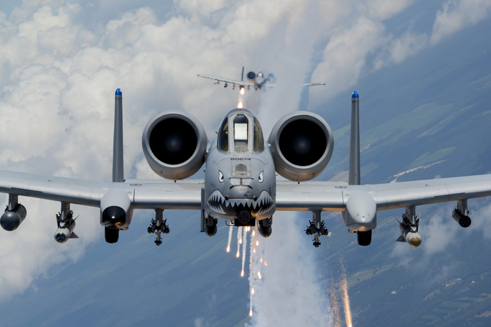 A fighter jet flying through the air with smoke coming out of its cockpit.