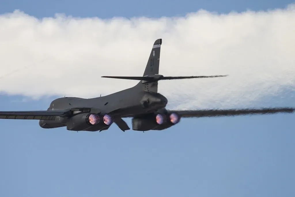 A jet fighter flying through the air with its landing gear down.