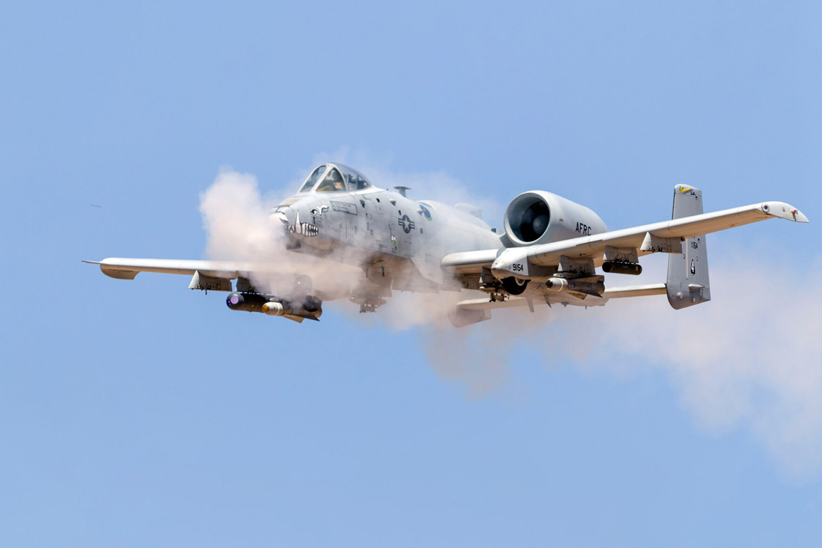 A plane is flying through the air with smoke coming out of it.