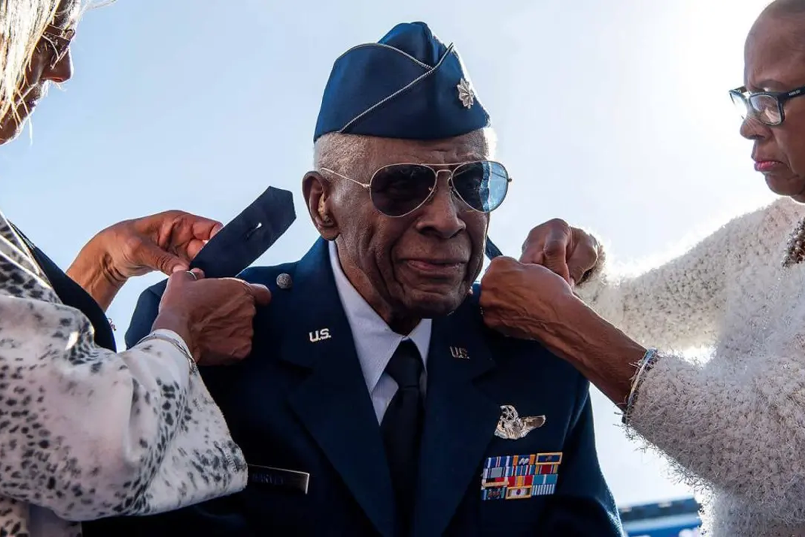 A man in uniform is putting on his hat.