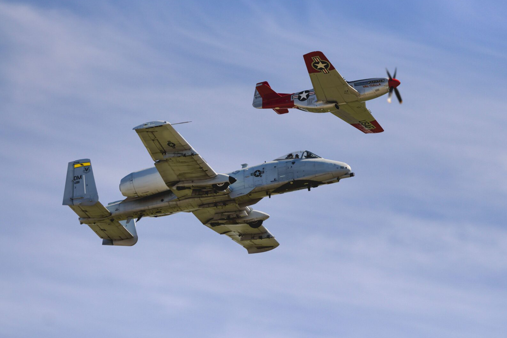 Two airplanes flying in the sky on a sunny day.