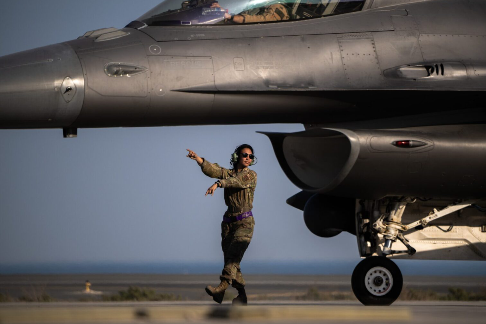 A man in military clothing standing next to an airplane.