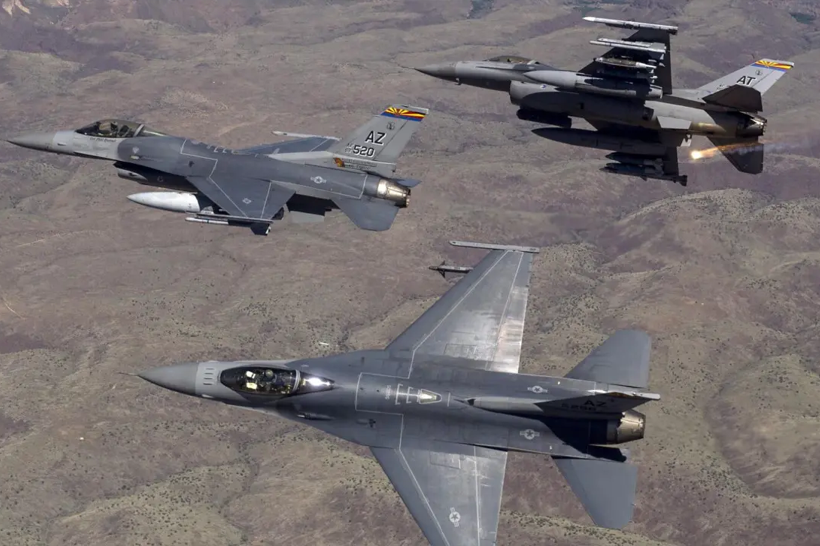 Three fighter jets flying in formation over the desert.