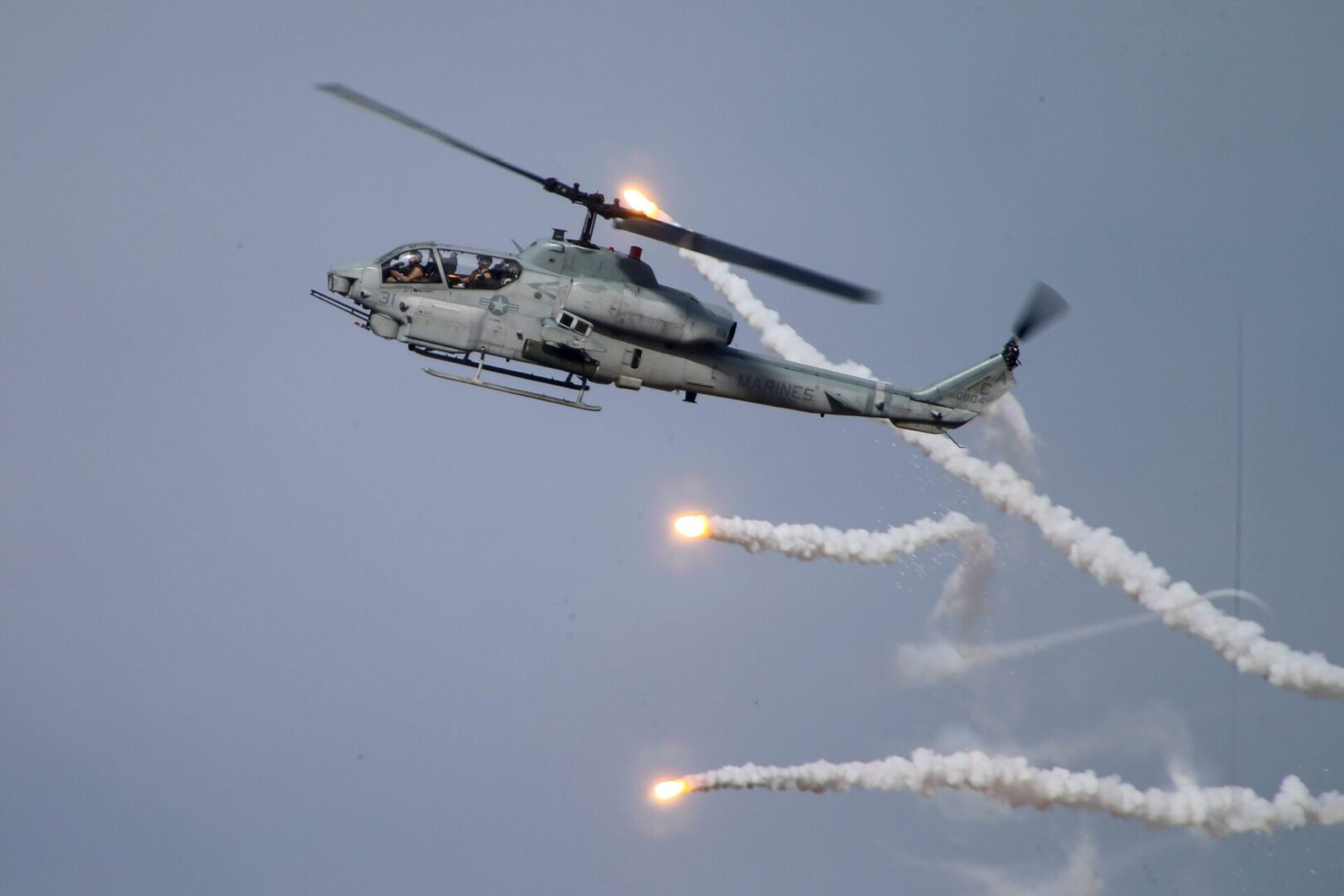 A helicopter flying in the sky with smoke coming out of it.