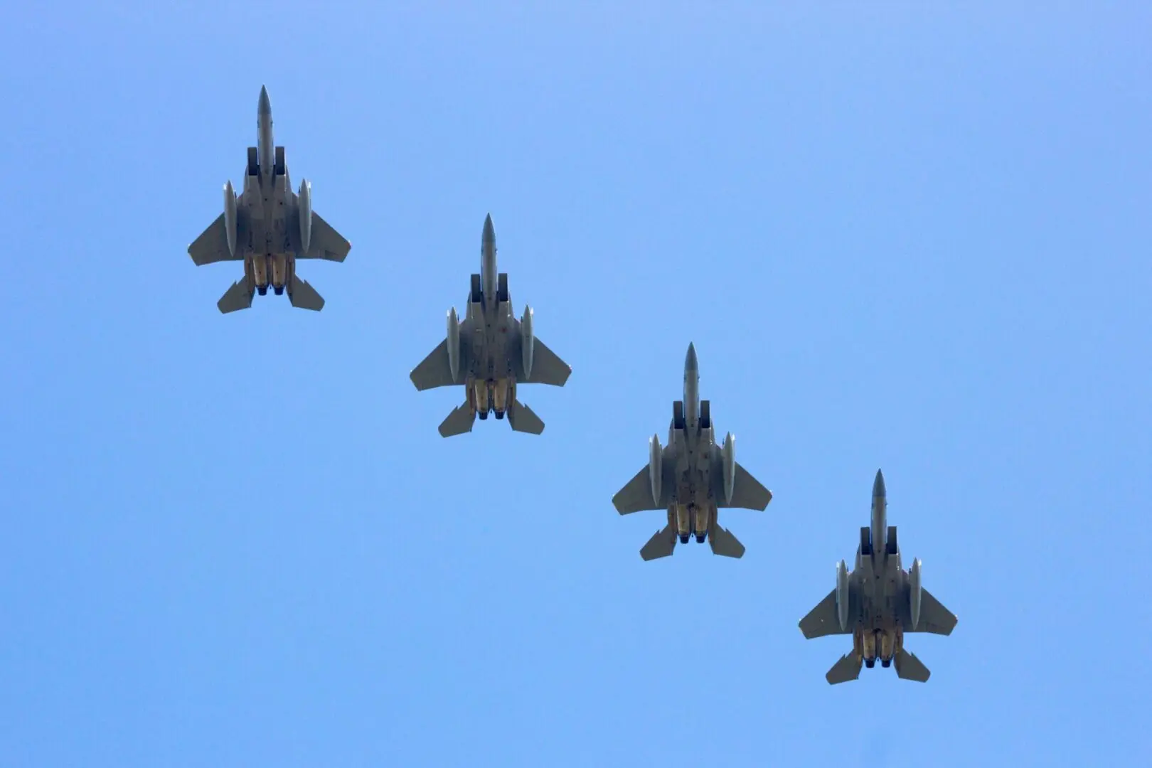 Four fighter jets flying in formation on a clear day.