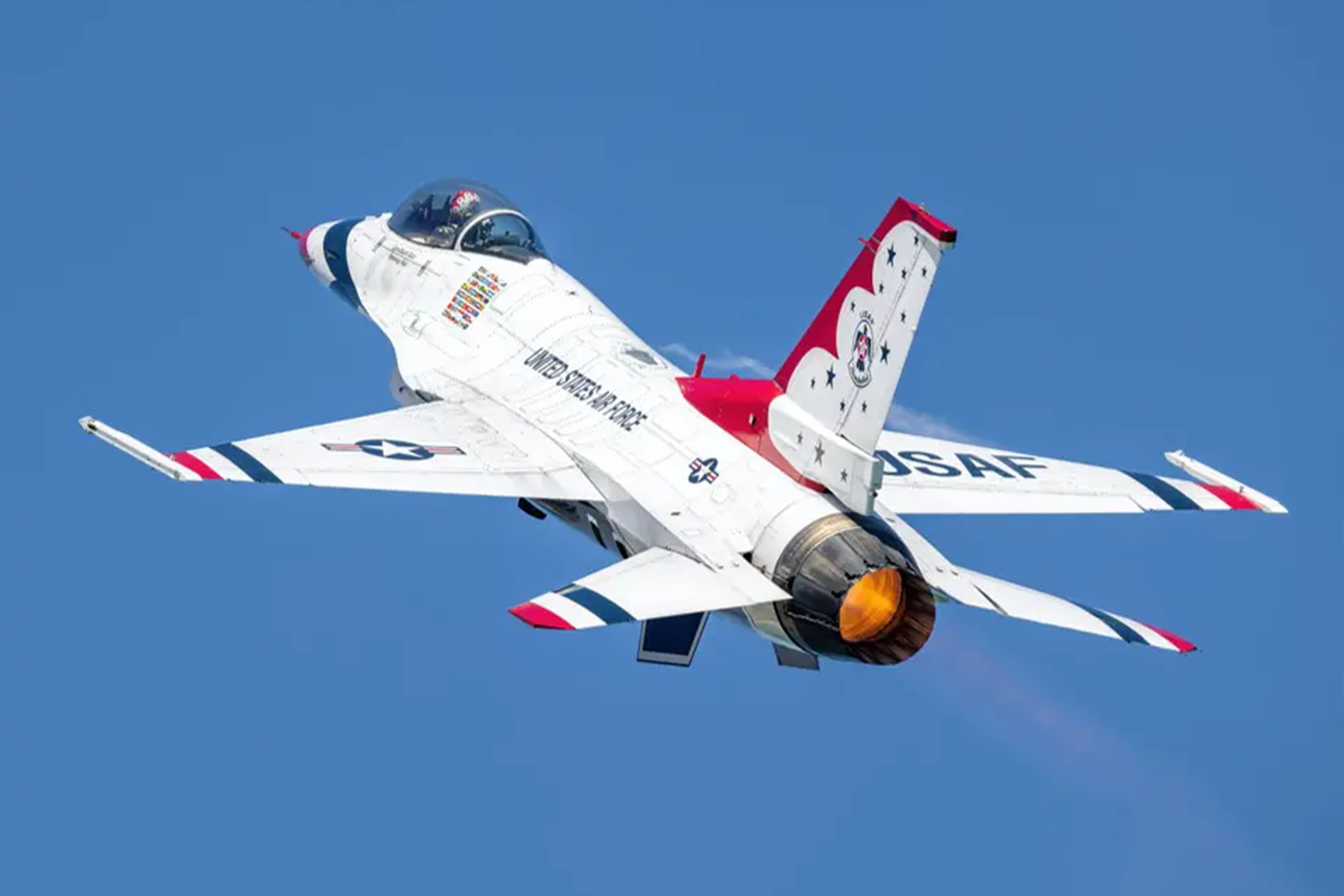 A fighter jet flying through the air with its landing gear down.